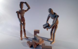 Zwei Figuren stehen vor einem Haufen Puzzleteile